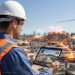 Construction workers collaborating on a busy jobsite with digital devices monitoring project progress